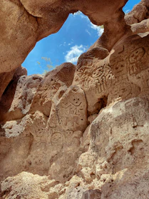 a rock formation with carvings on it and a sky background