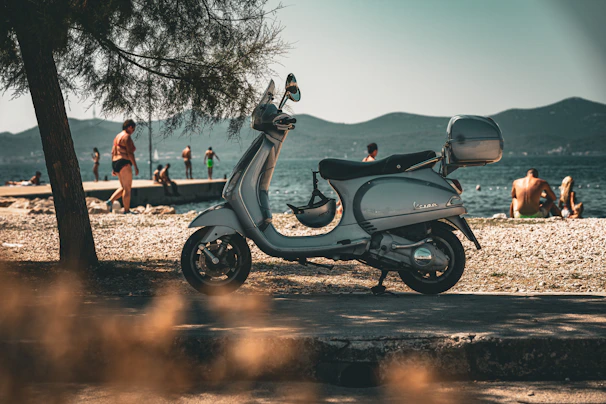 A vintage Vespa parked on a sunlit Amalfi Coast street near the sea.