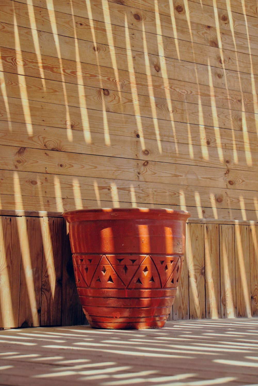 a large red pot sitting next to a wooden wall