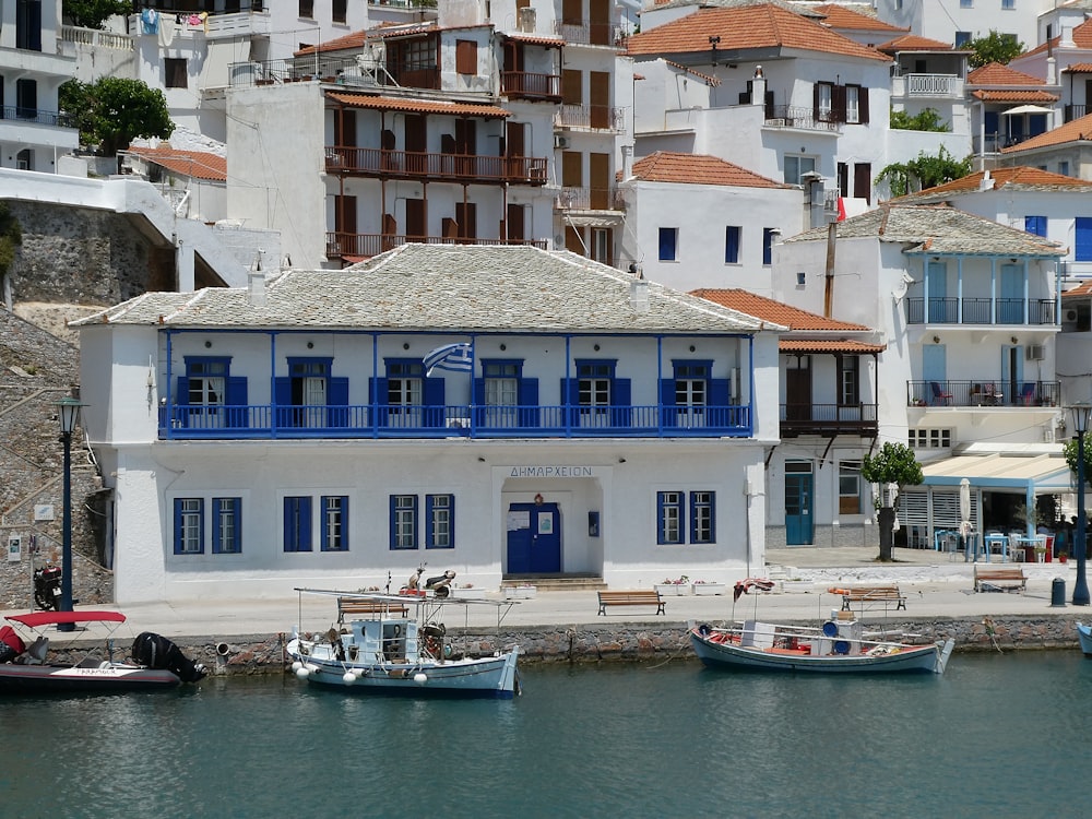 a white building with blue shutters next to a body of water