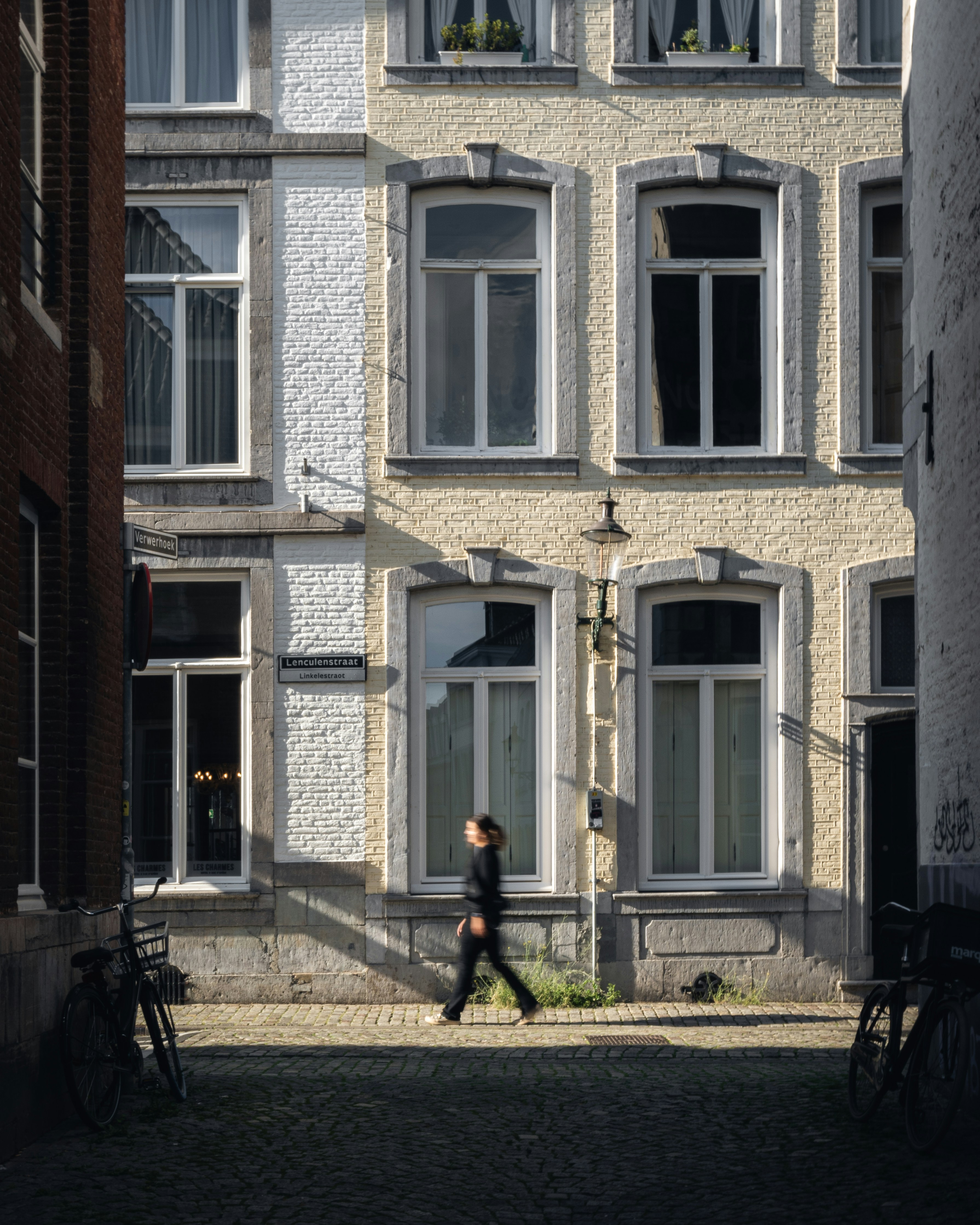 a person walking down a street past a tall building