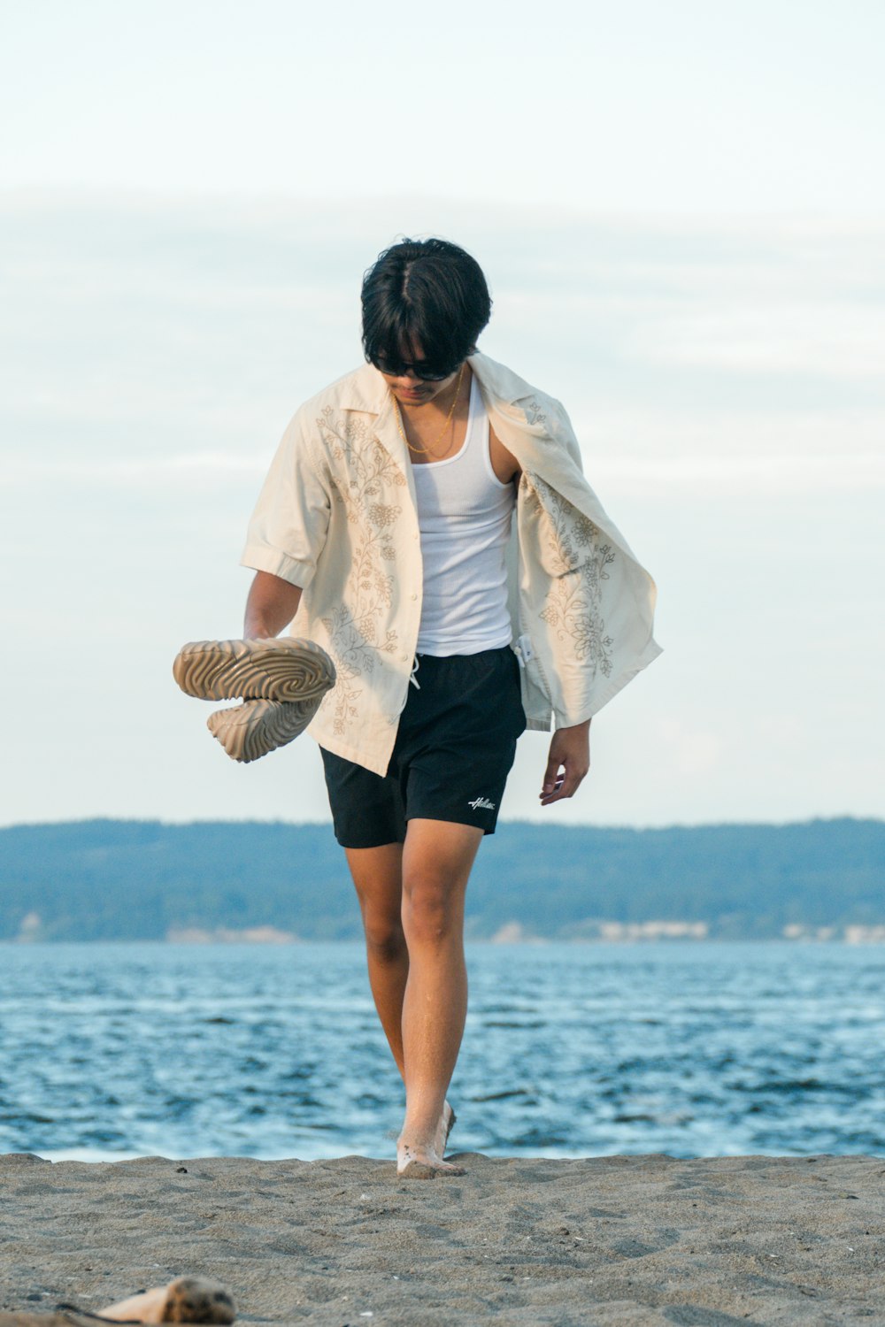 a woman walking on a beach next to the ocean