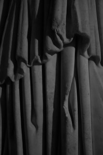 Detailed folds and drapery likely from a sculpture or piece of fabric, with shadowing that creates a sense of depth and texture.