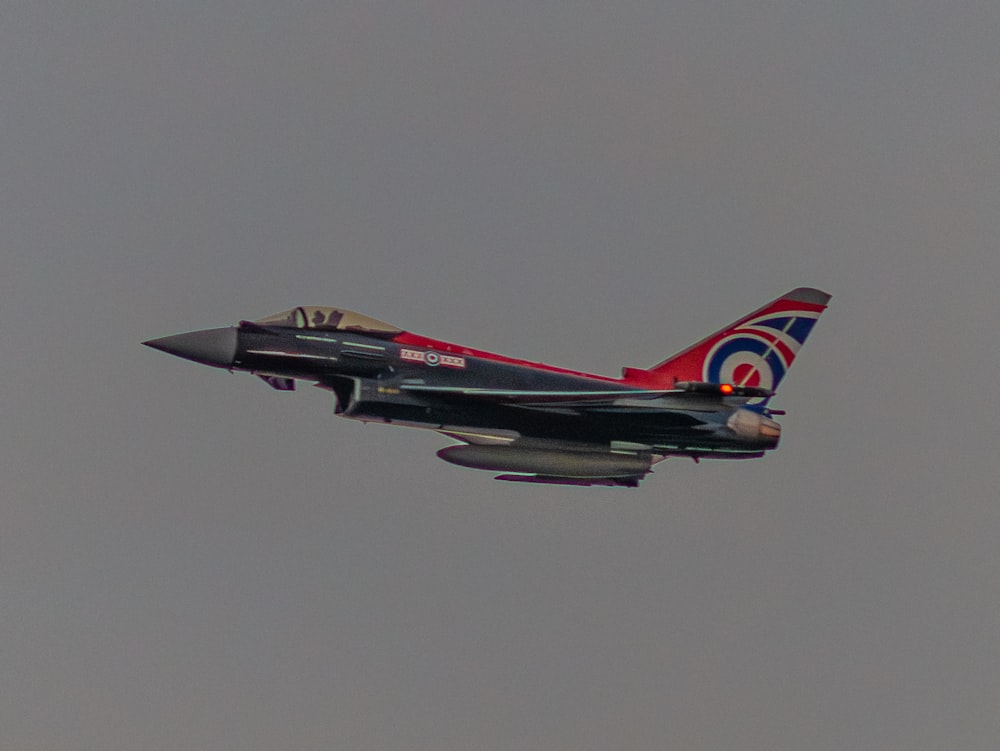 a fighter jet flying through a gray sky