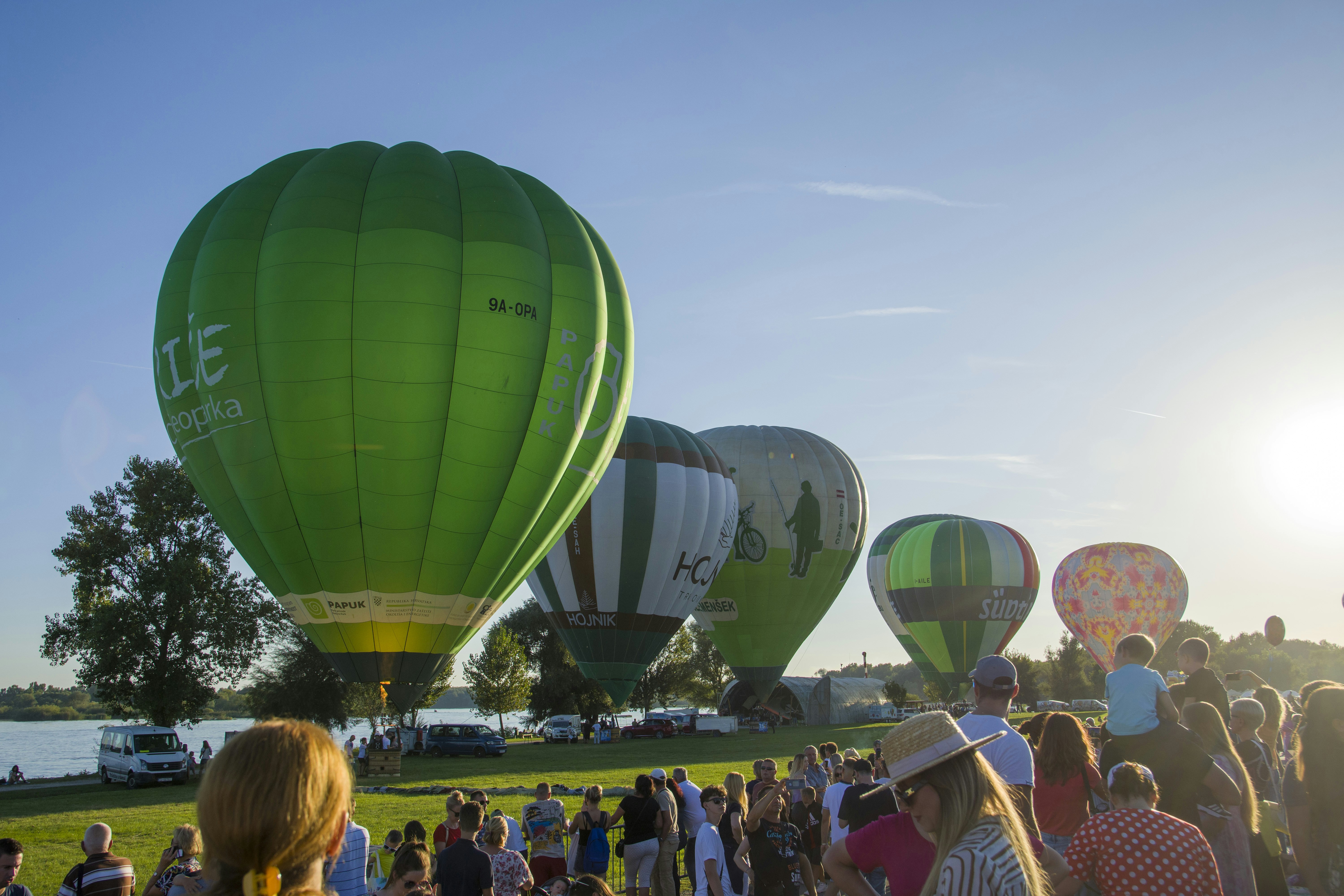 eine Gruppe von Menschen, die um Heißluftballons herum stehen