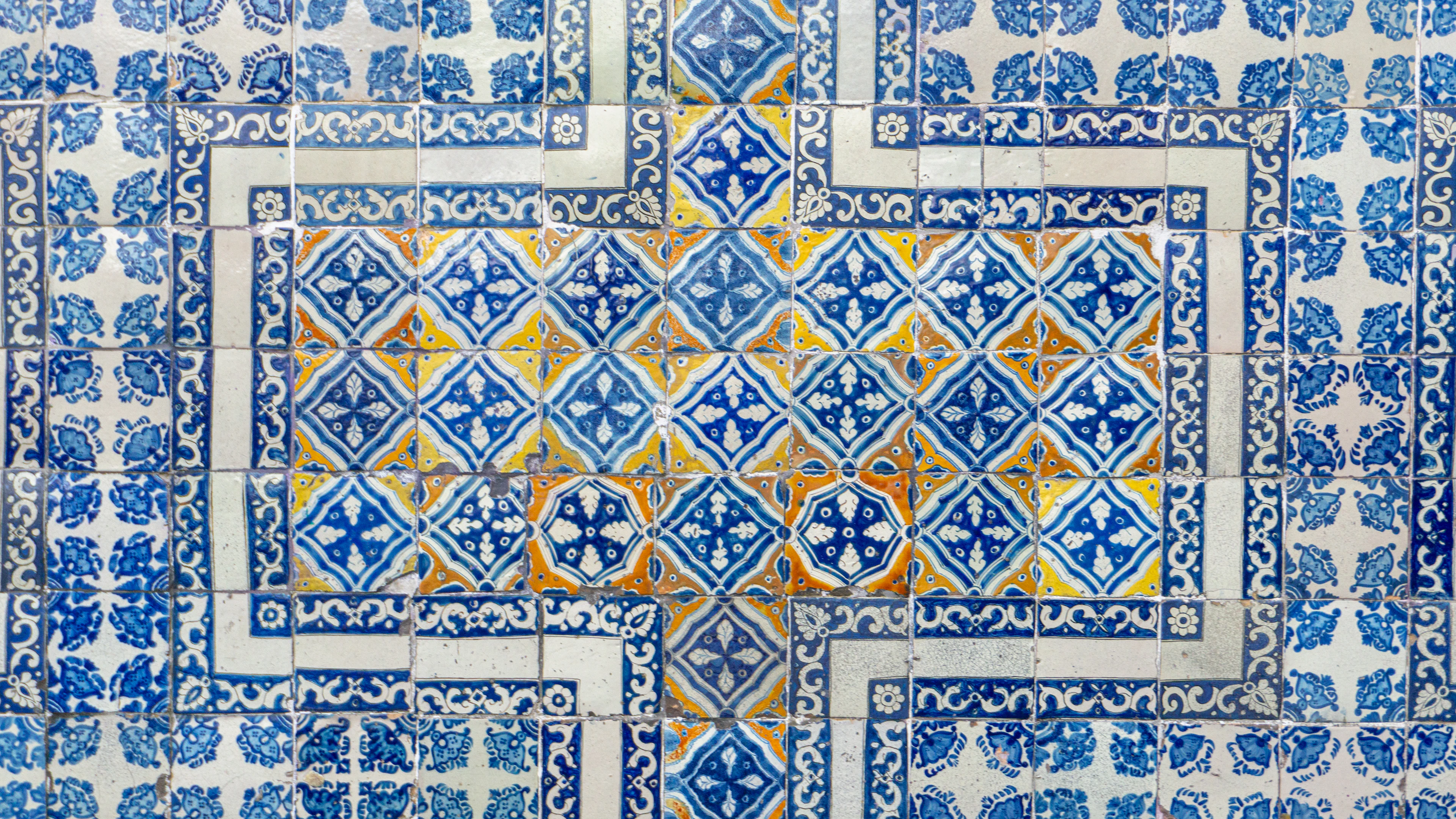 A wall of blue and white tiles with an intricate painted design.