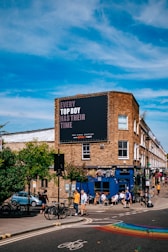 a group of people walking across a street next to a tall building