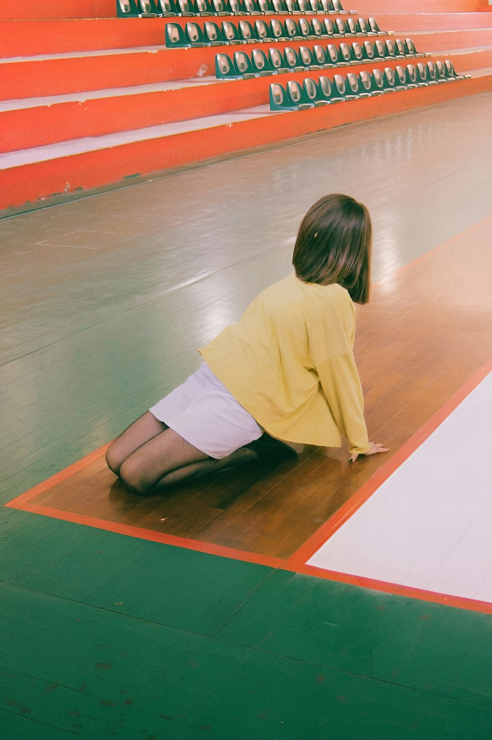 a young girl sitting on the floor of a gymnasium
