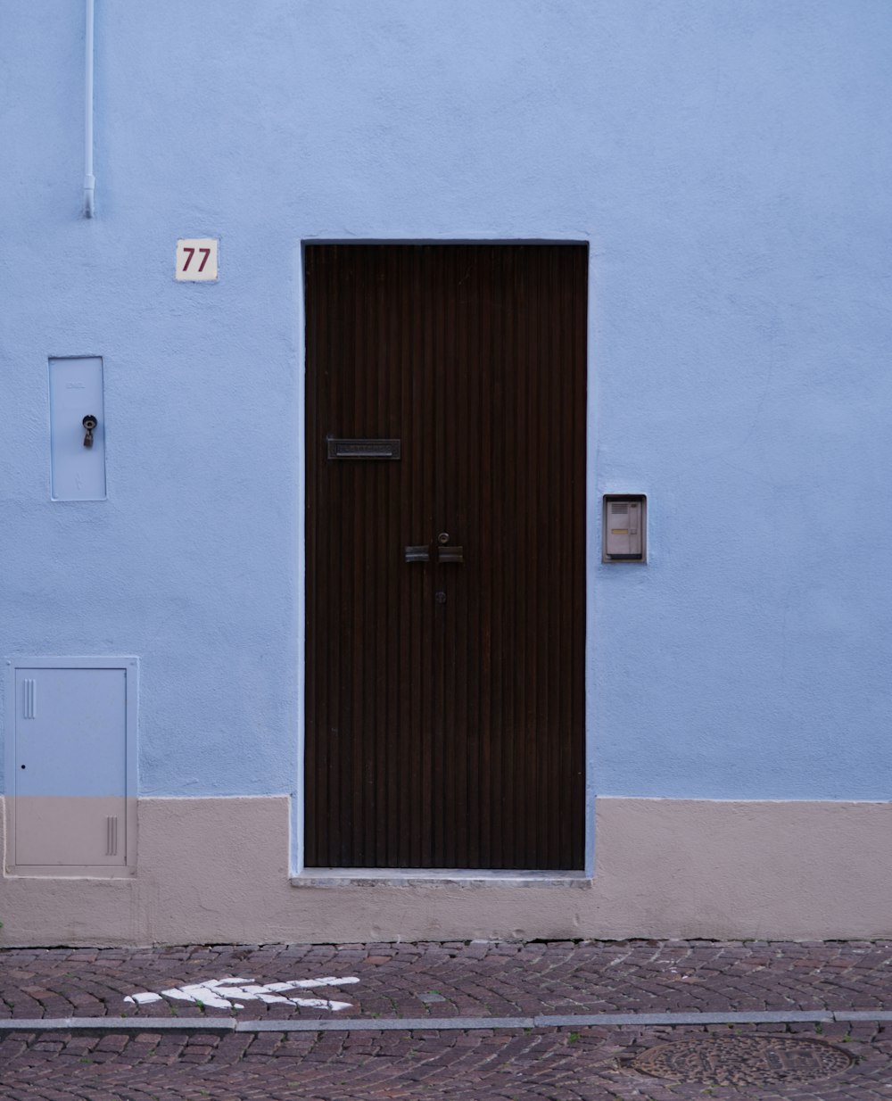a blue building with a black door and a white fire hydrant
