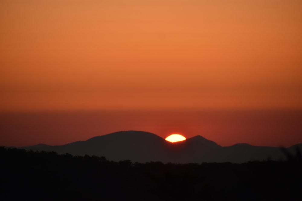 the sun is setting over a mountain range