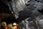 A rocky underground environment, likely a cave or mine, with layered mineral formations visible on the walls. Several individuals wearing yellow hard hats and safety vests can be seen, indicating a guided tour or exploration activity.