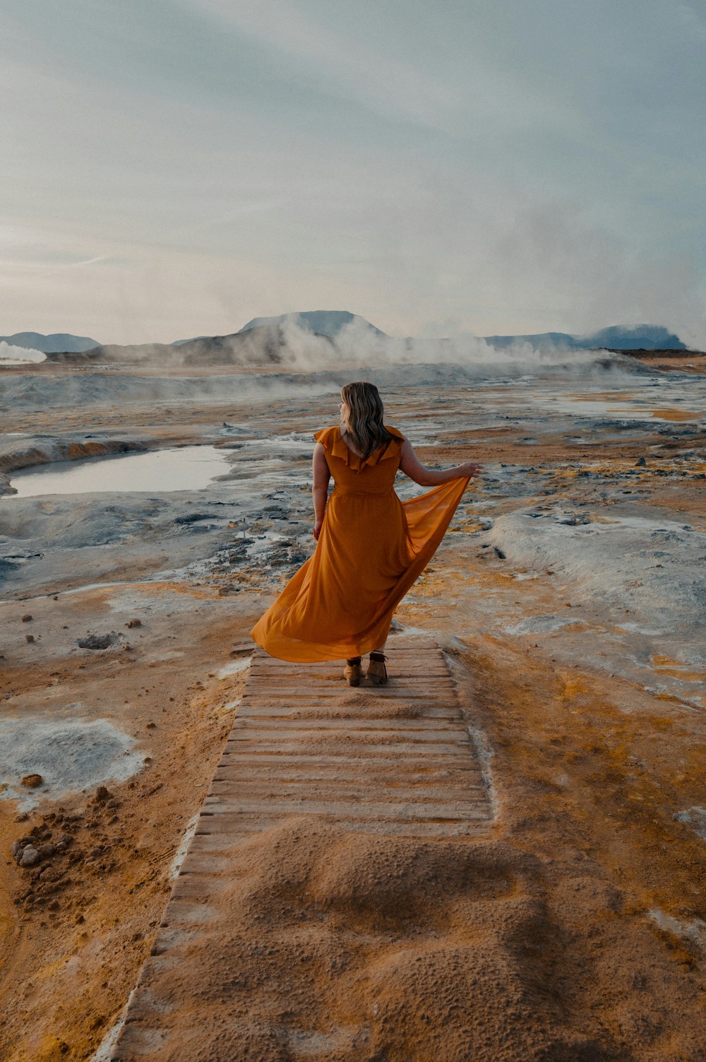 a woman in an orange dress walking up a flight of stairs