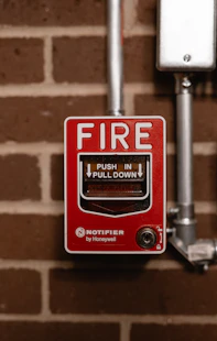 a red fire button on a brick wall