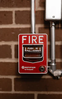 a red fire button on a brick wall