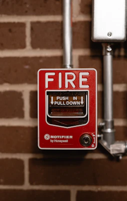 a red fire button on a brick wall