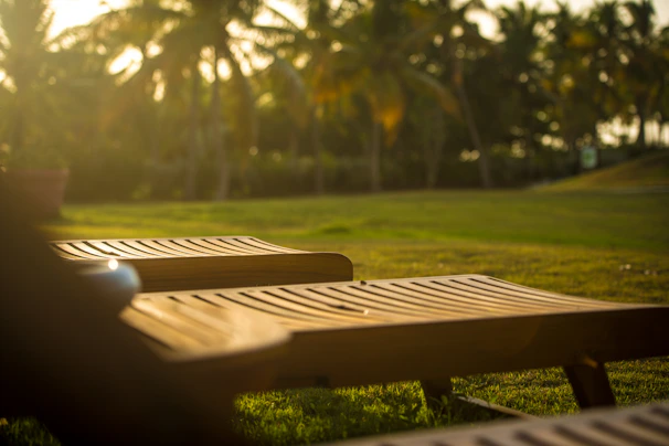 A peaceful outdoor scene showing a wooden lounge chair basking in golden sunlight.