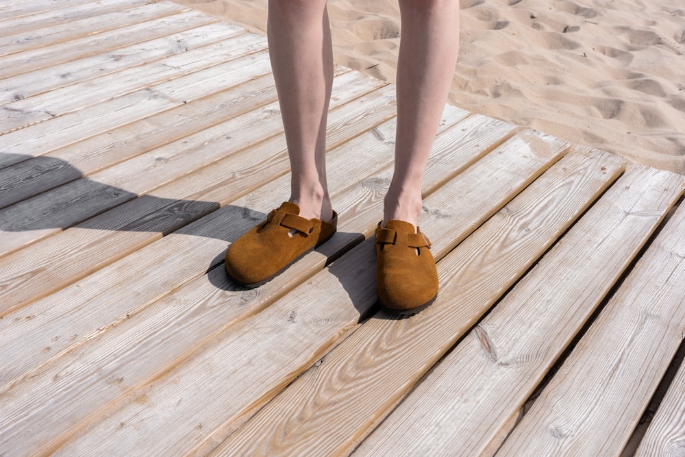 a person standing on a wooden dock wearing brown shoes