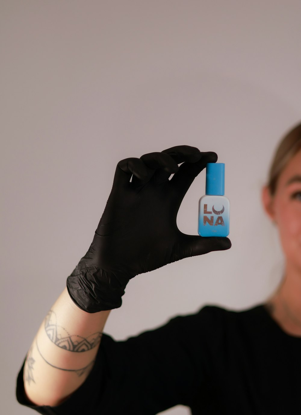 a woman in black shirt holding up a small blue object