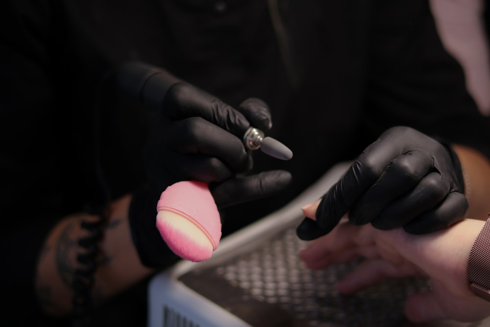 a person in black gloves holding a pink object