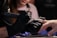 A person wearing black gloves is using a nail drill on someone else's finger. The focus is on the hands and the nail treatment process, suggesting a manicure or nail care session.