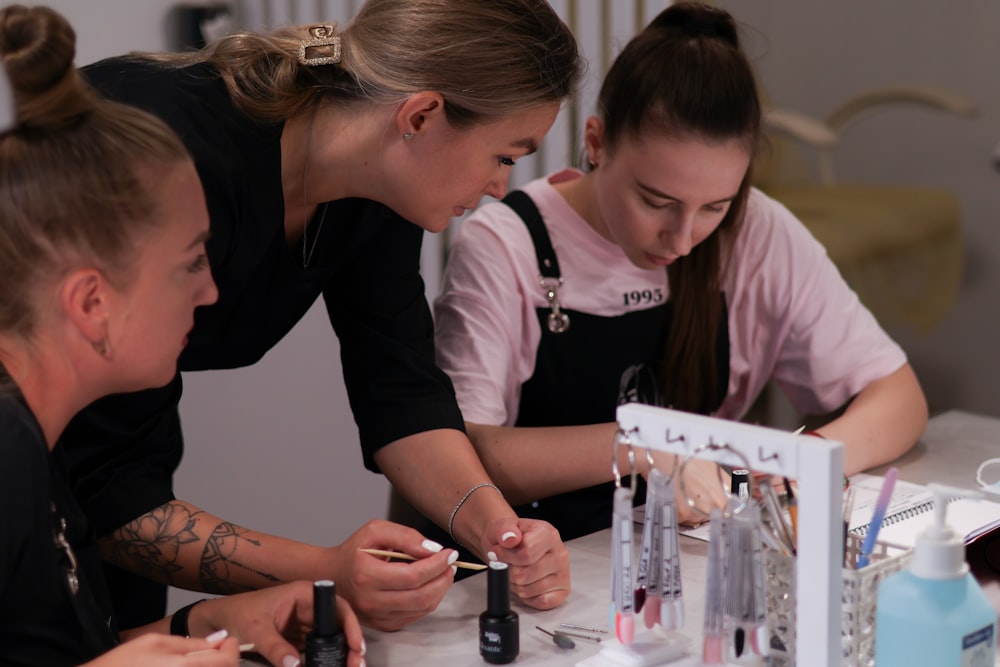 a group of women sitting around a table working on nail polish