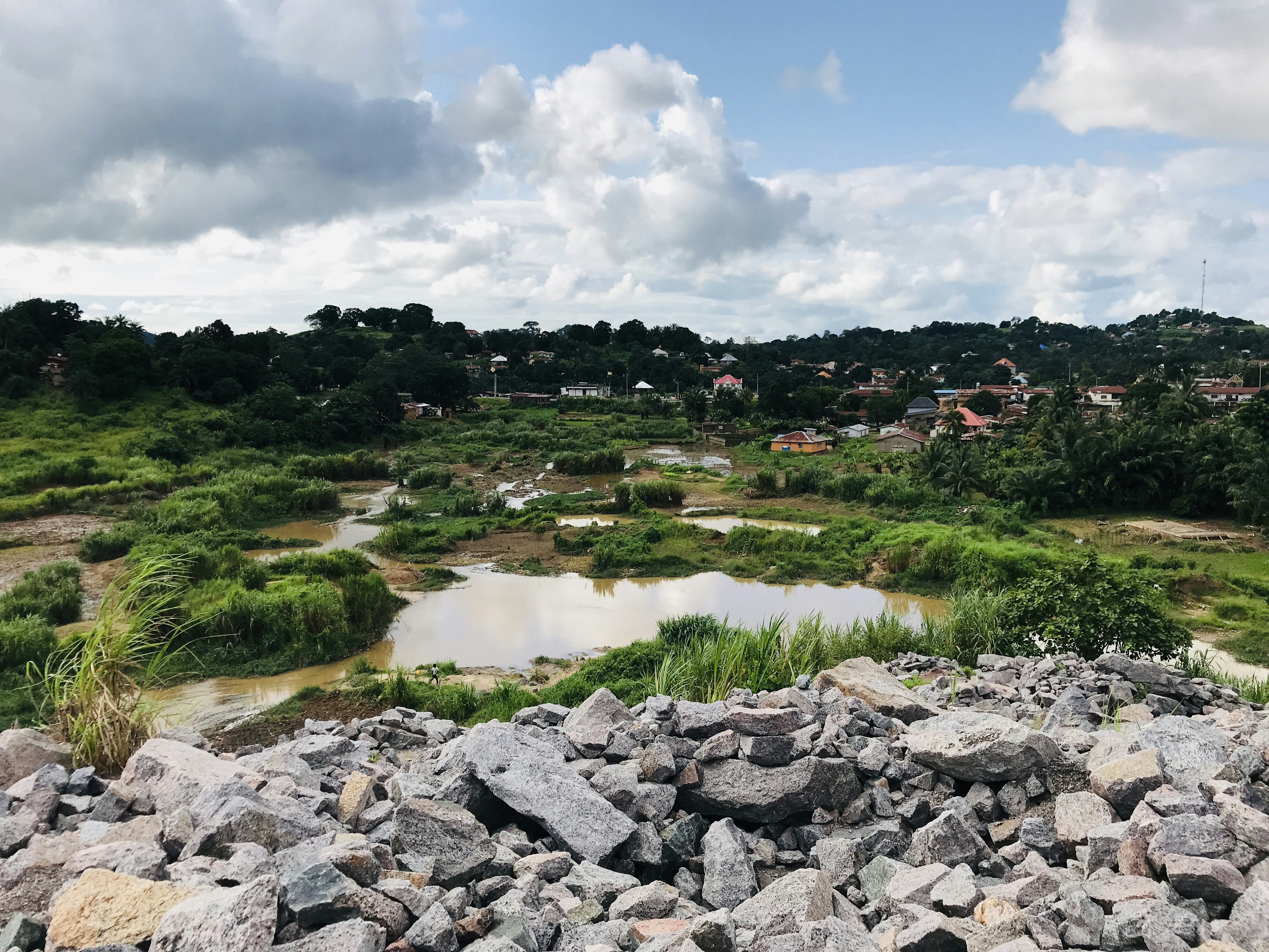 a large pile of rocks sitting on top of a lush green hillside