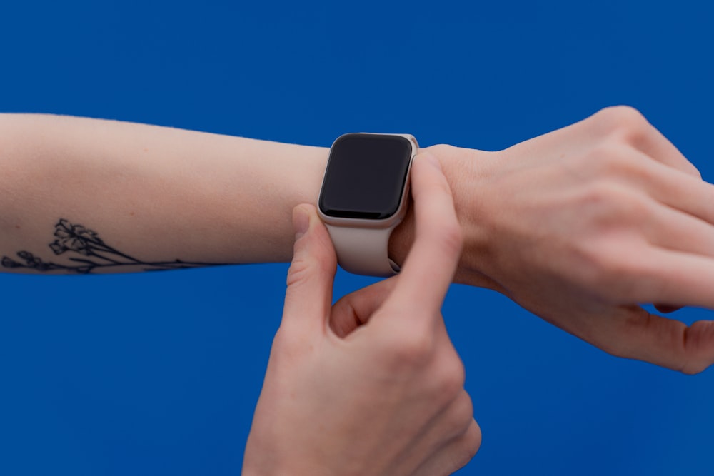 a person with a tattoo on their arm holding an apple watch