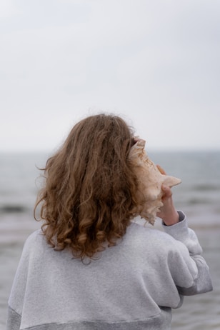 a woman holding a seashell up to her face
