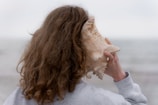 a woman with long hair holding a seashell up to her face