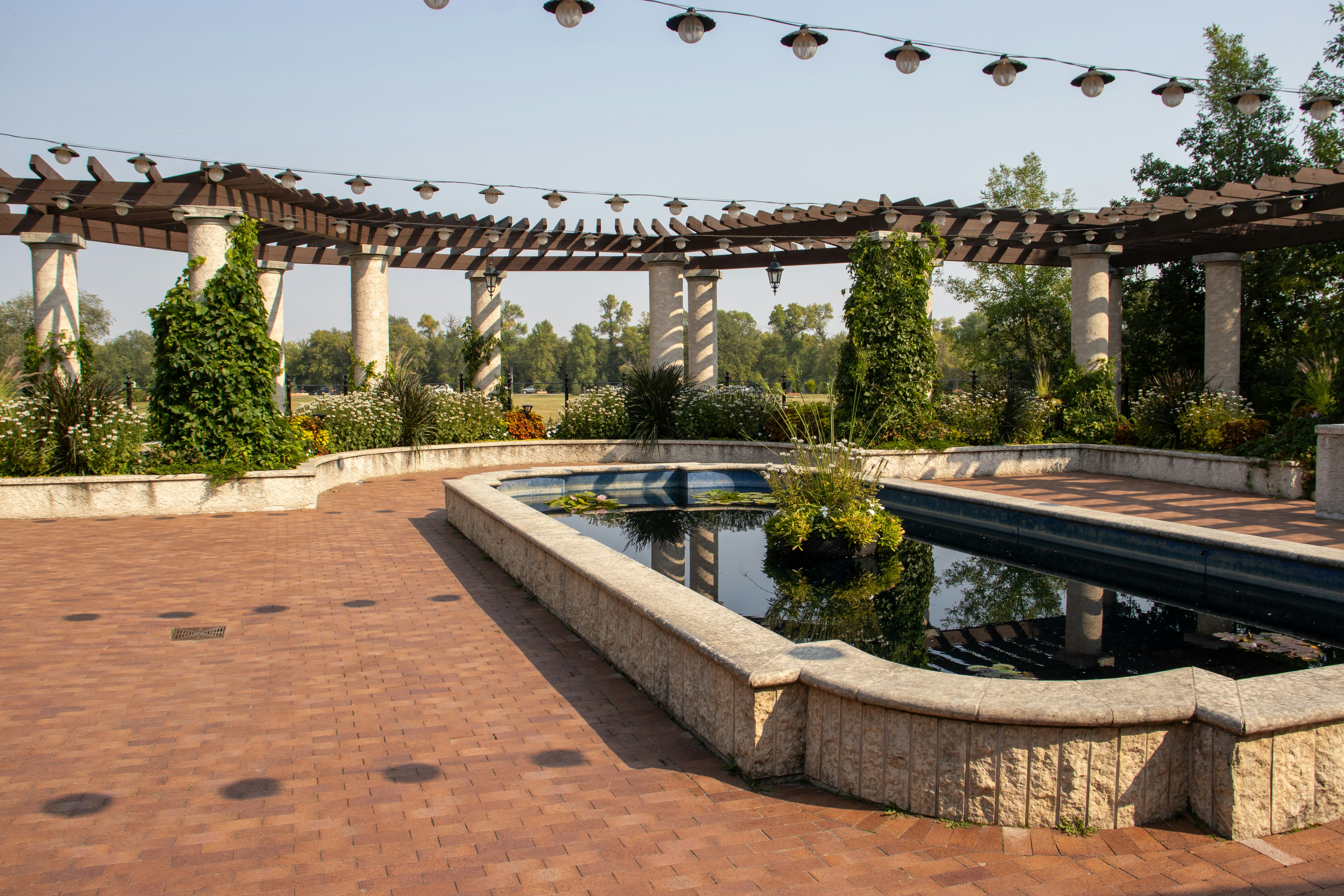 a brick patio with a pool and a pergolated area