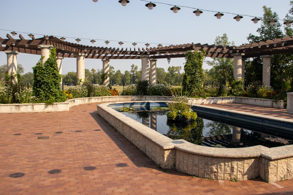 a brick patio with a pool and a pergolated area