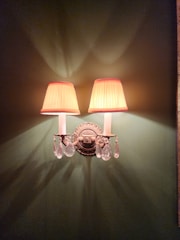 Elegant metal wall sconces with clear glass shades softly illuminating a hallway.