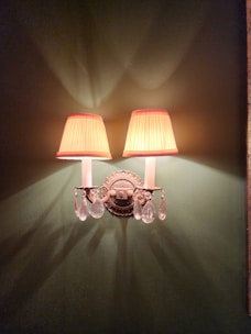 Elegant metal wall sconces with clear glass shades softly illuminating a hallway.
