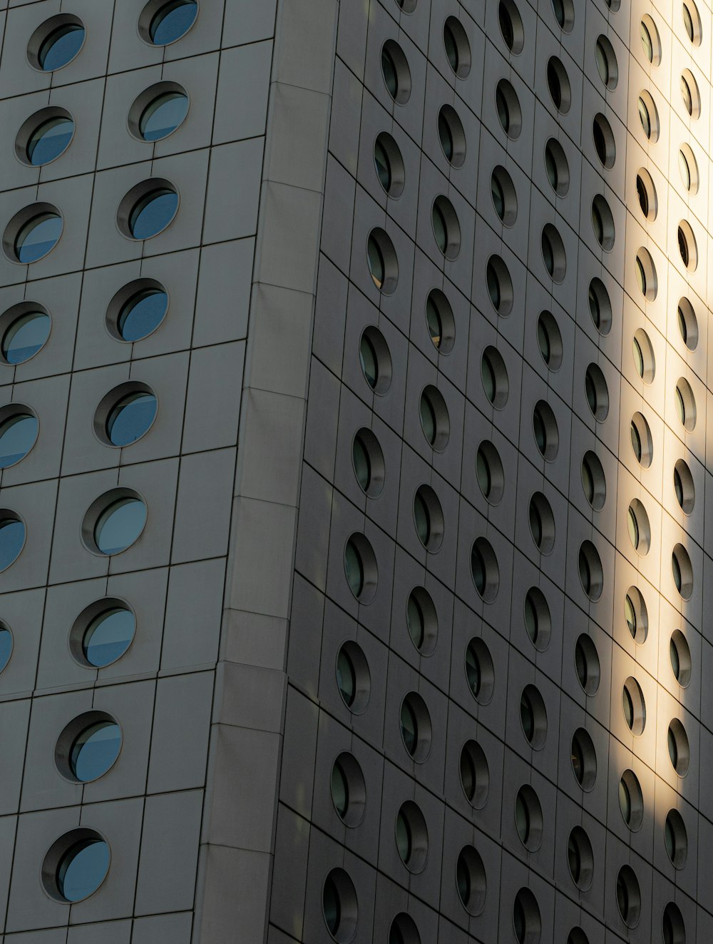 a tall building with many round windows and a clock on the side