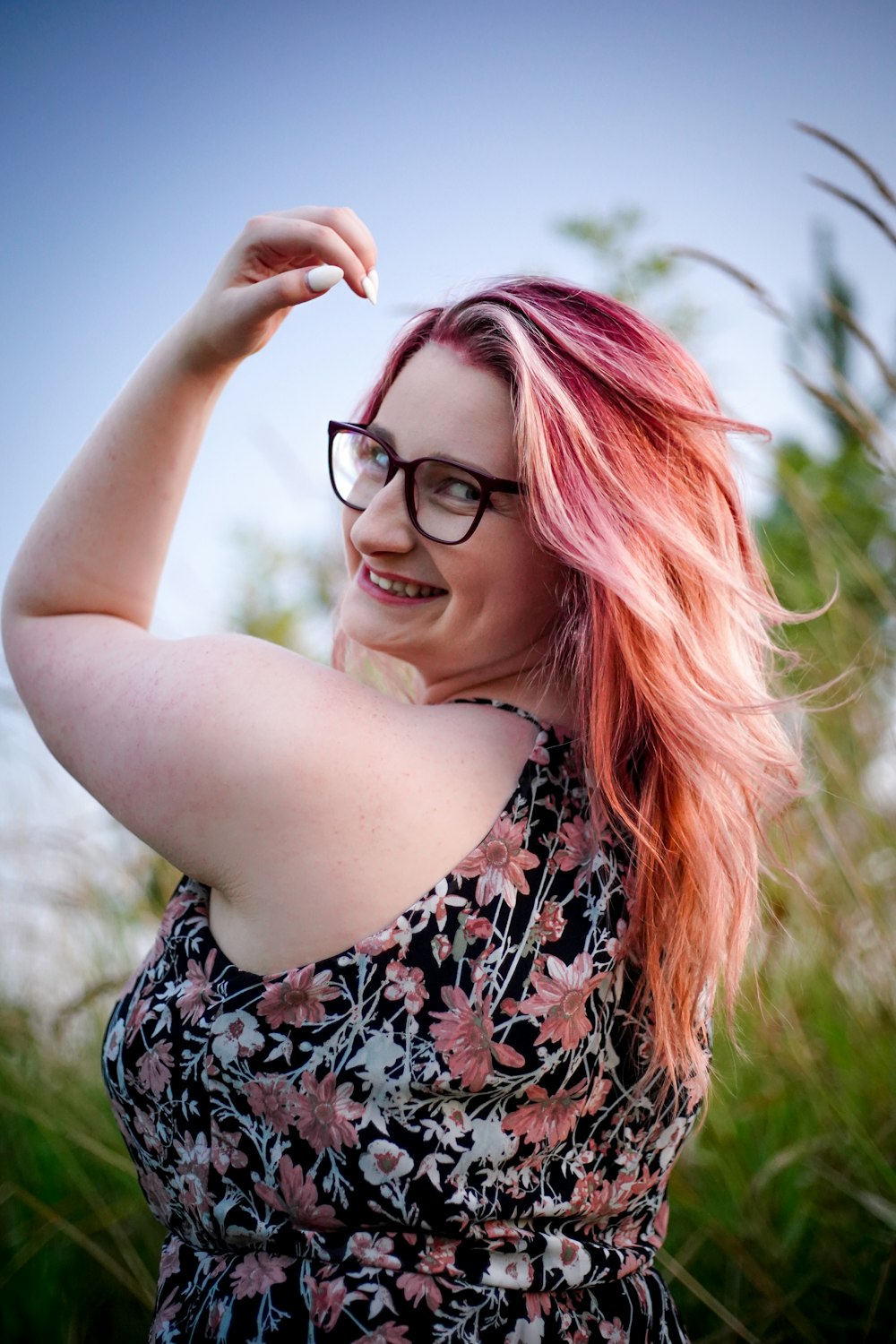 a woman with pink hair and glasses posing for a picture