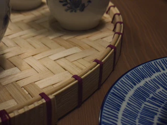 Close-up of biodegradable sugarcane bagasse plates and ultra-soft bamboo tissues arranged on a sand beige surface with subtle leaf patterns.