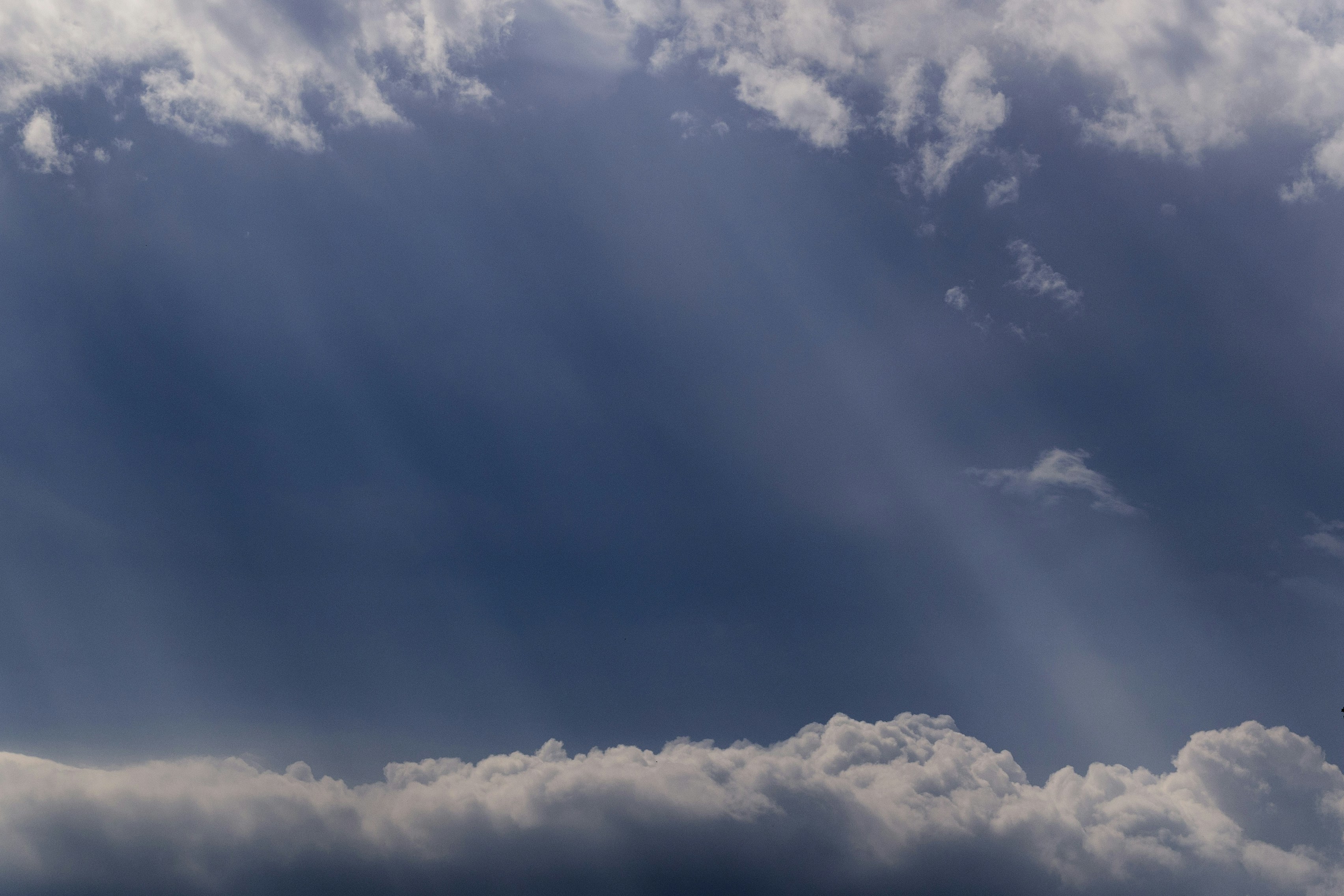 a plane flying through a cloudy blue sky