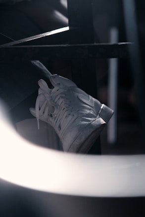 Close-up of a skilled technician carefully cleaning a luxury sneaker in a sleek, dark navy and gold-themed workshop.