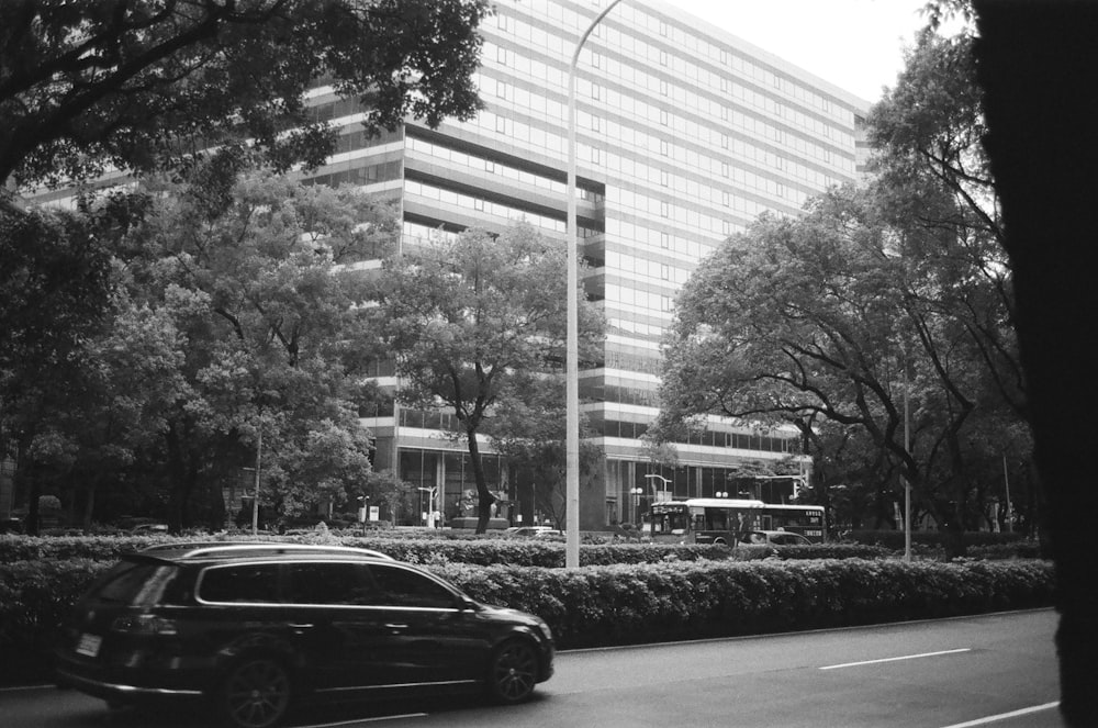 a car driving down a street next to a tall building