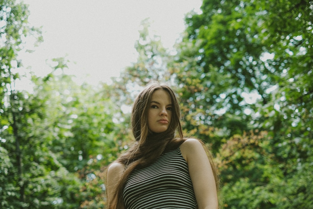 a woman standing in a forest with trees in the background