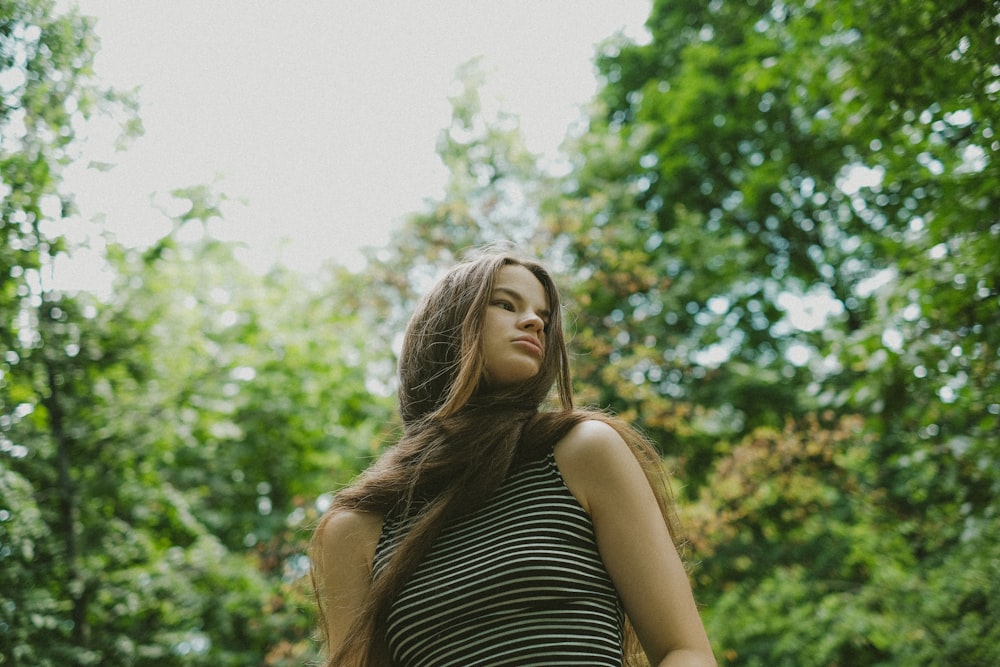 a woman standing in the woods with her hair blowing in the wind