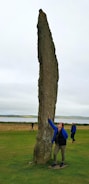 A geobiologist measuring magnetic fields with specialized equipment near an ancient stone structure