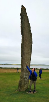 A geobiologist measuring magnetic fields with specialized equipment near an ancient stone structure