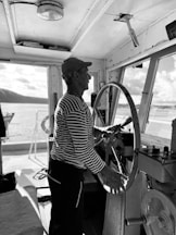 a man standing at the wheel of a boat