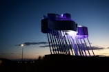 Evening view of a completed outdoor metal sculpture illuminated by soft lights.