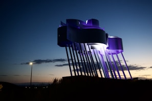 Evening view of a completed outdoor metal sculpture illuminated by soft lights.