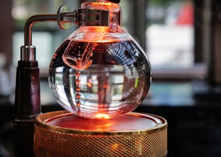 Sleek stainless steel distillation equipment glowing softly against a black background with neon yellow accents.