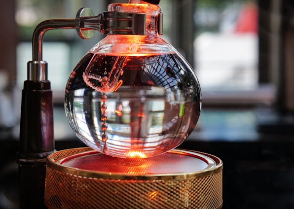 Sleek stainless steel distillation equipment glowing softly against a black background with neon yellow accents.