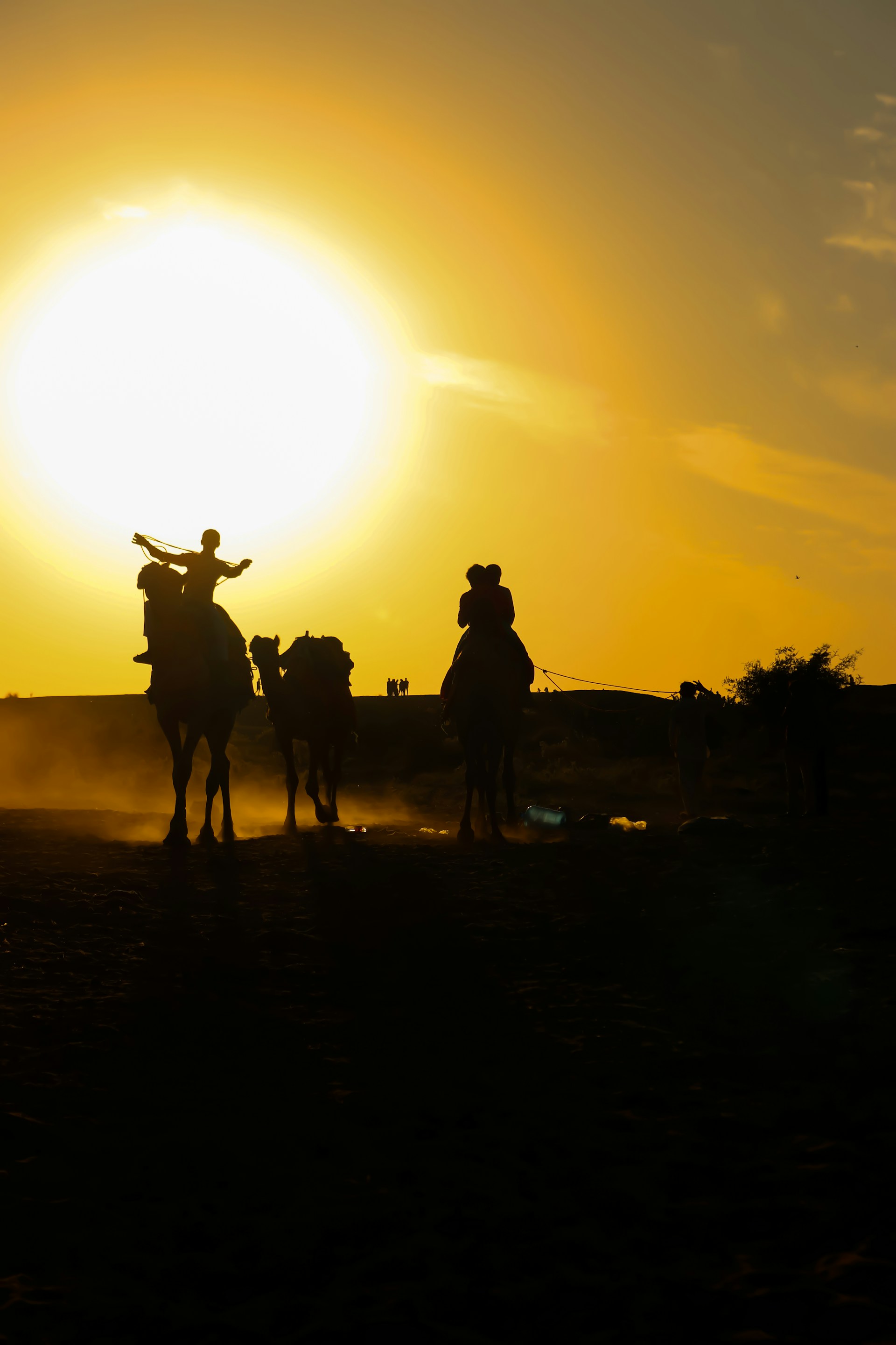 A vibrant sunset over the Sahara dunes with travelers riding camels in a golden light.