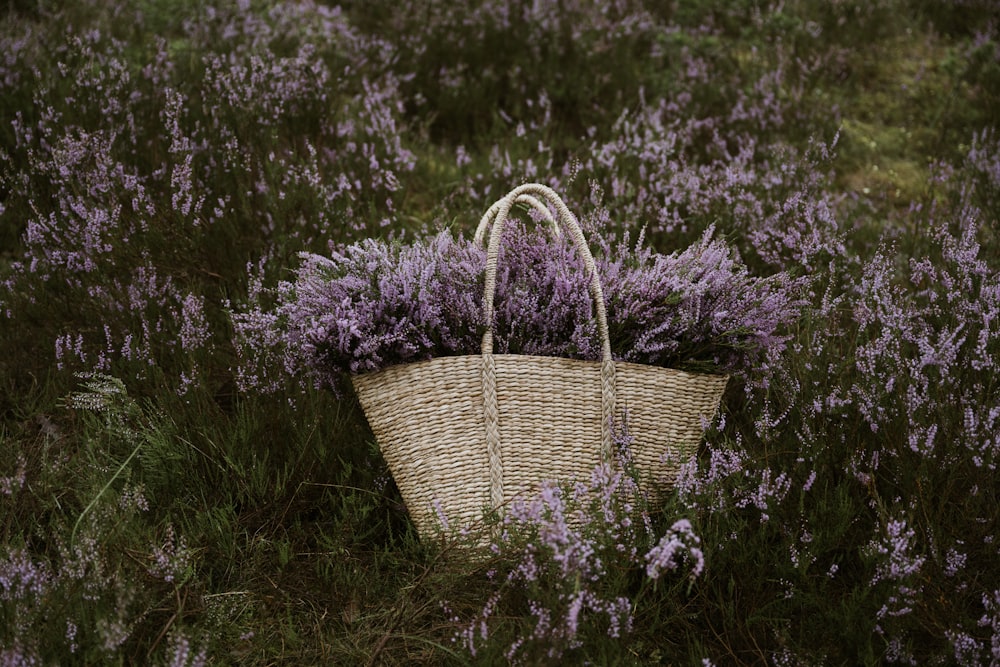 a wicker basket with purple flowers in a field